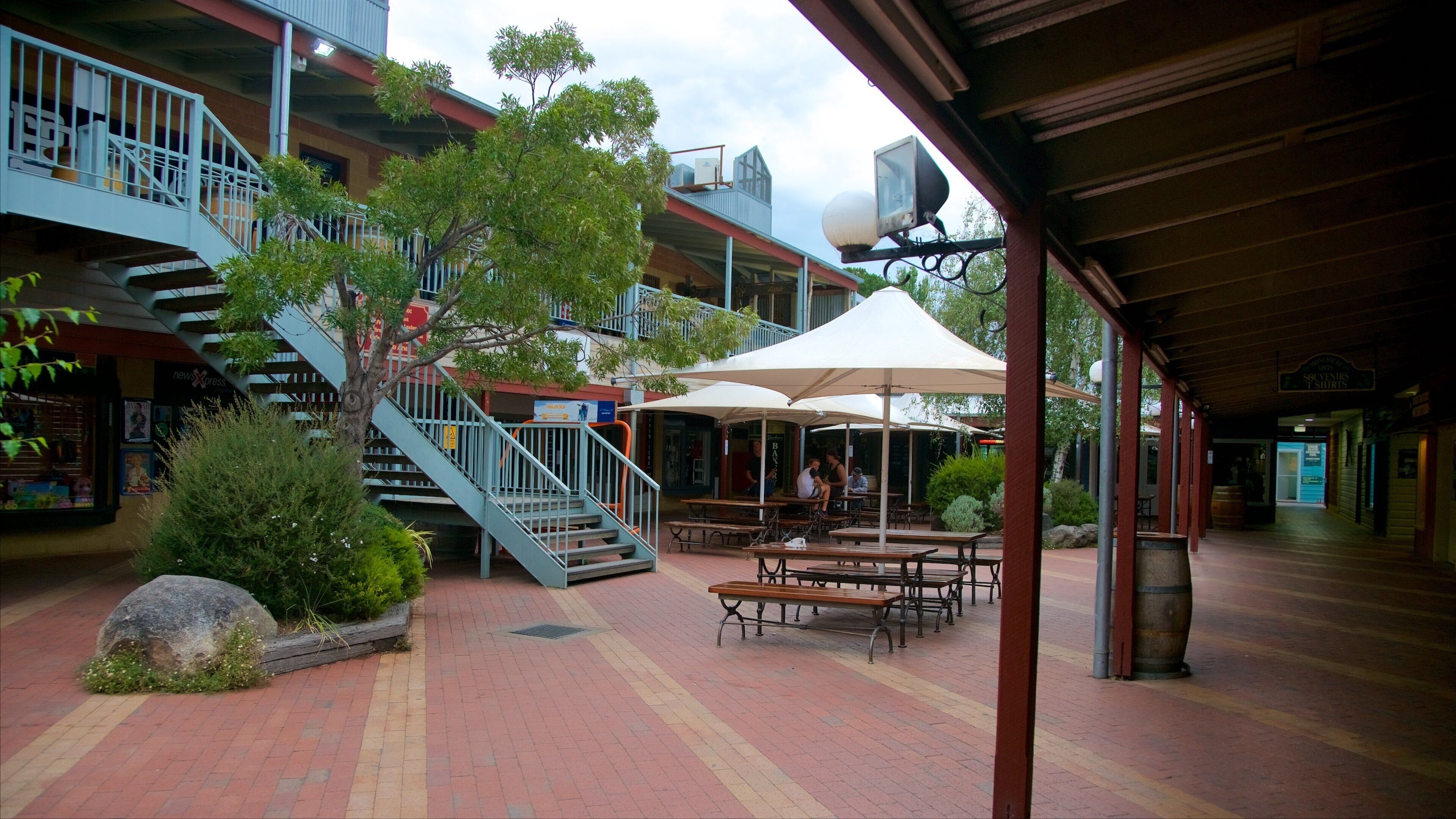 A covered outdoor area with a staircase, benches, and umbrellas.