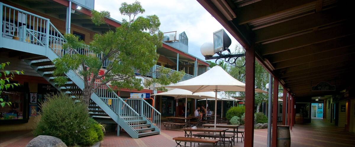 A covered outdoor area with a staircase, benches, and umbrellas.