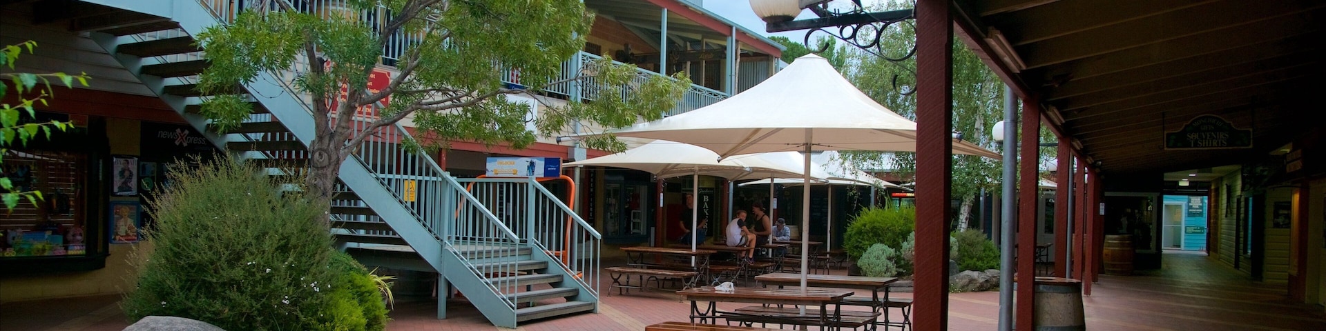 A covered outdoor area with a staircase, benches, and umbrellas.