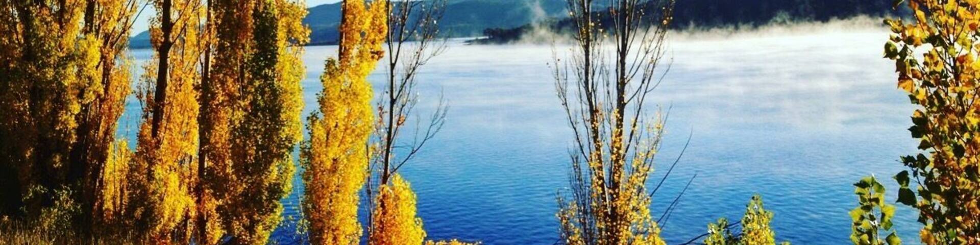 A lake surrounded by autumn trees with yellow leaves.