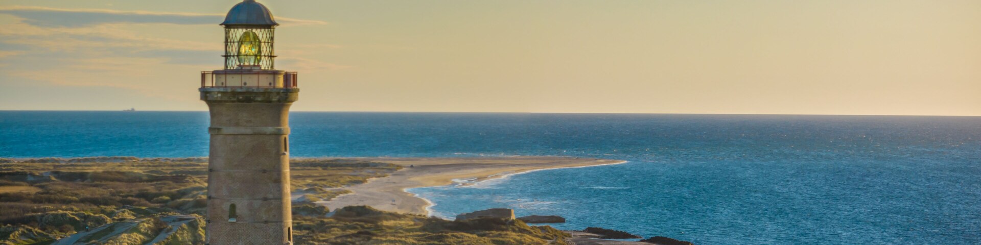 Un paisaje costero con un faro, una playa y una costa rocosa.