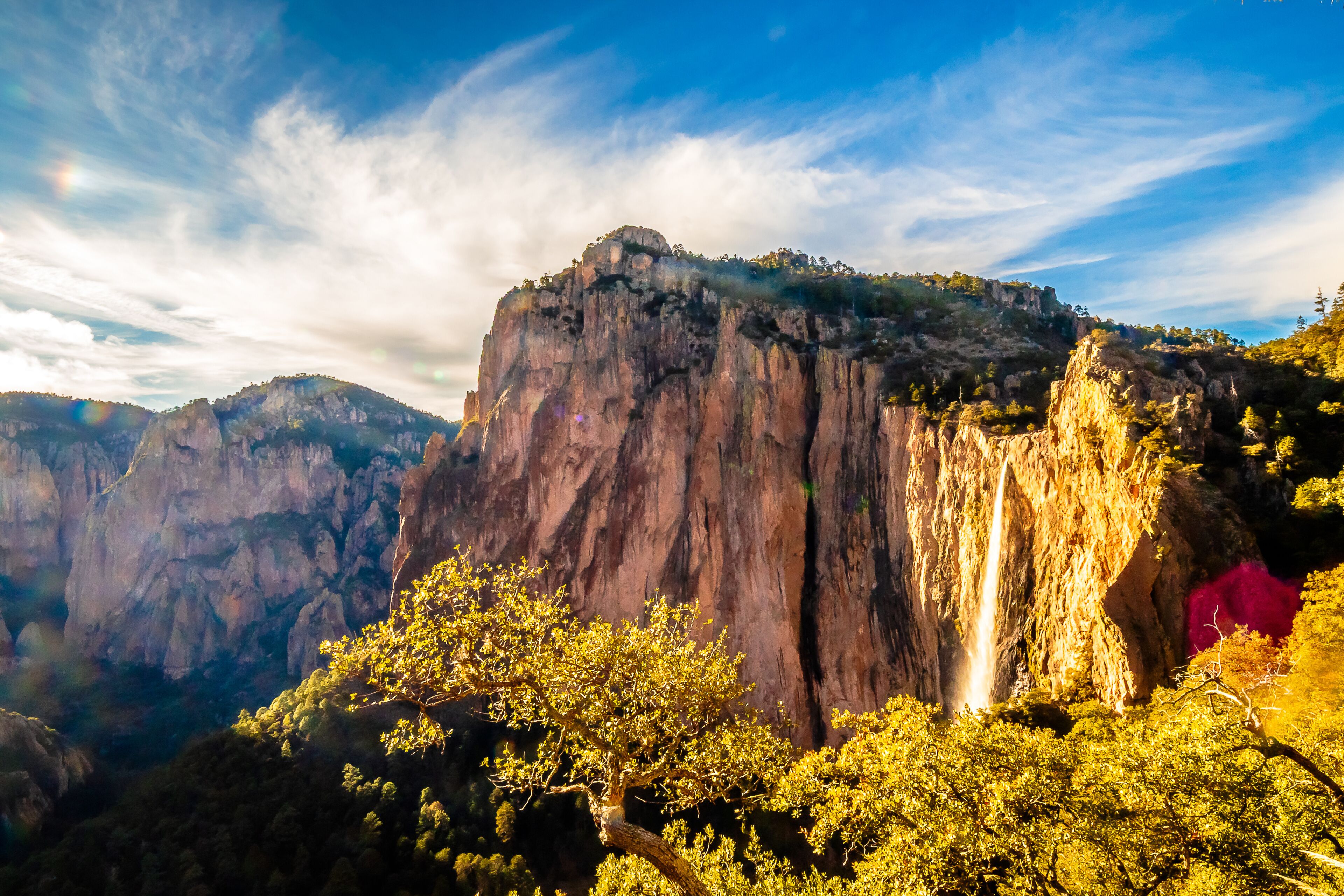 A mountain with a waterfall and dense forest.