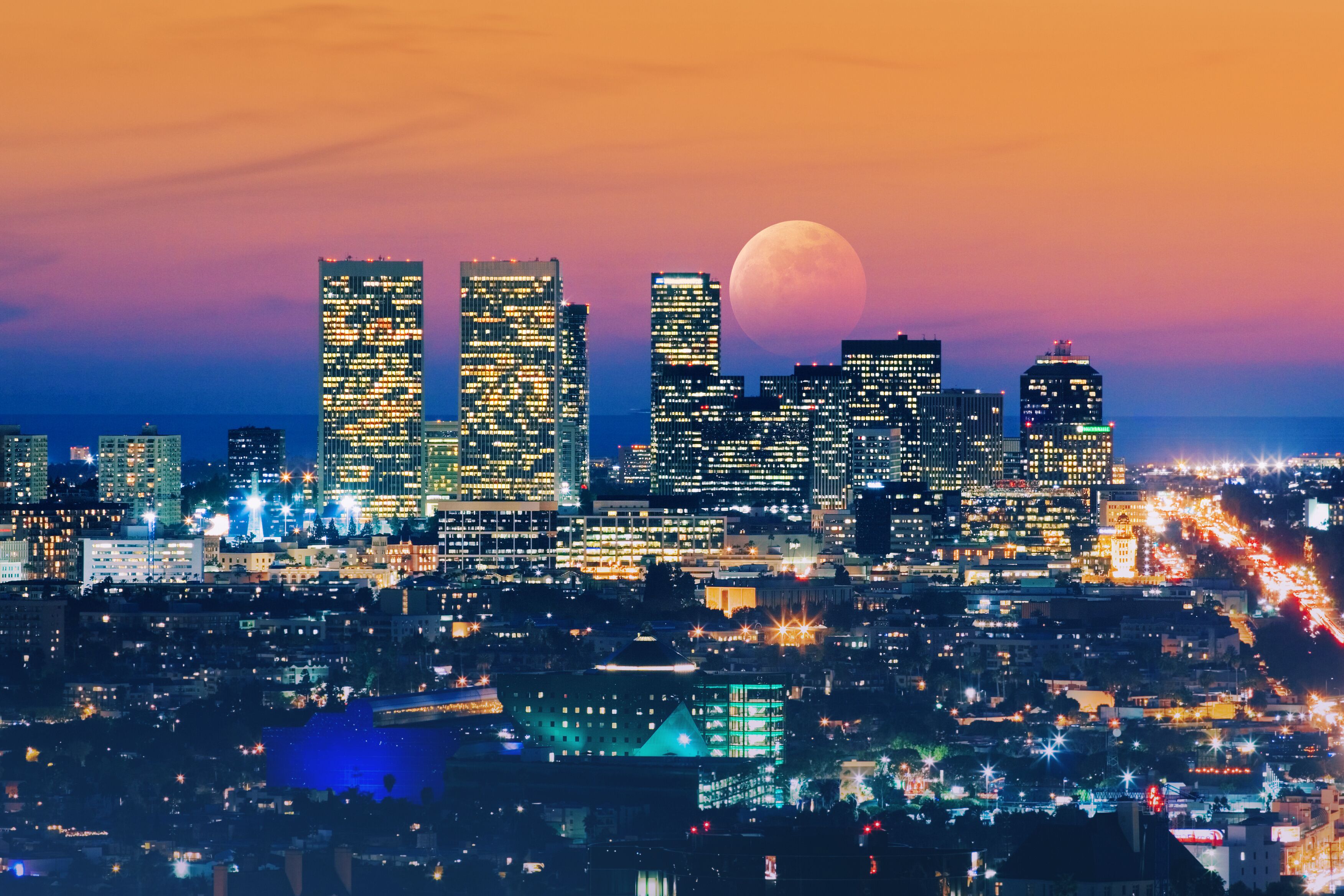 Ful moon rising over Los Angeles skyline at night