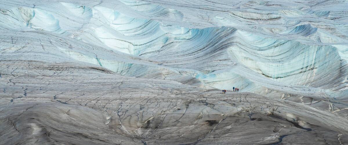 A geological formation with layered rock strata and a small group of people in the distance.