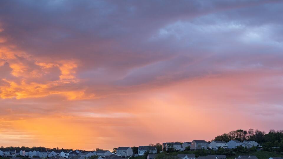 Vivid sunrise colors illuminate clouds over suburban houses outside Pittsburgh