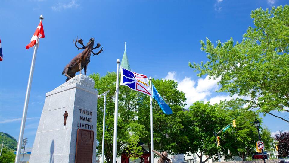 A statue of a reindeer on a stone monument with flags and a clear blue sky.
