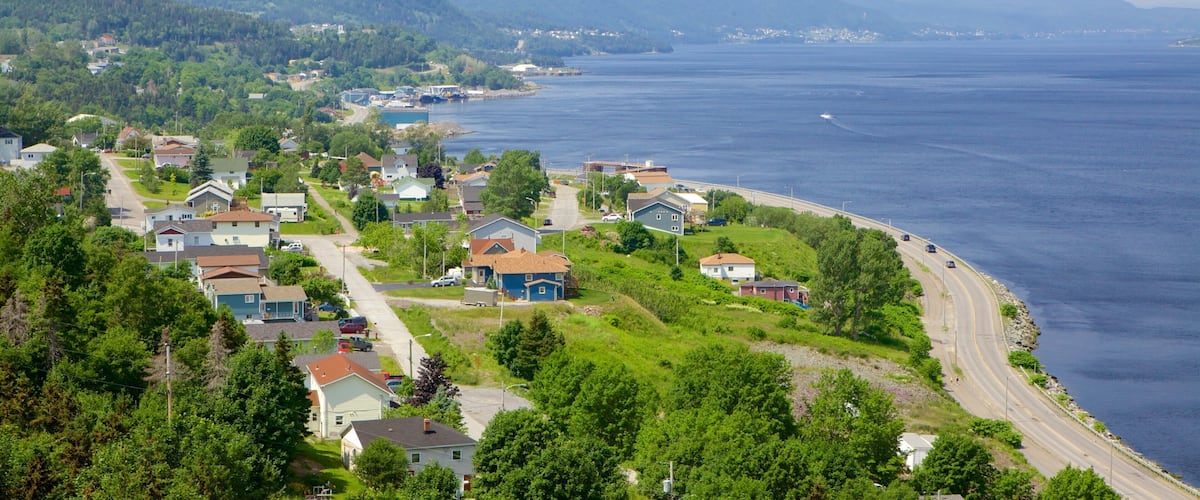 A coastal town with houses along the shoreline, a road curving through the town, and mountains in the background.