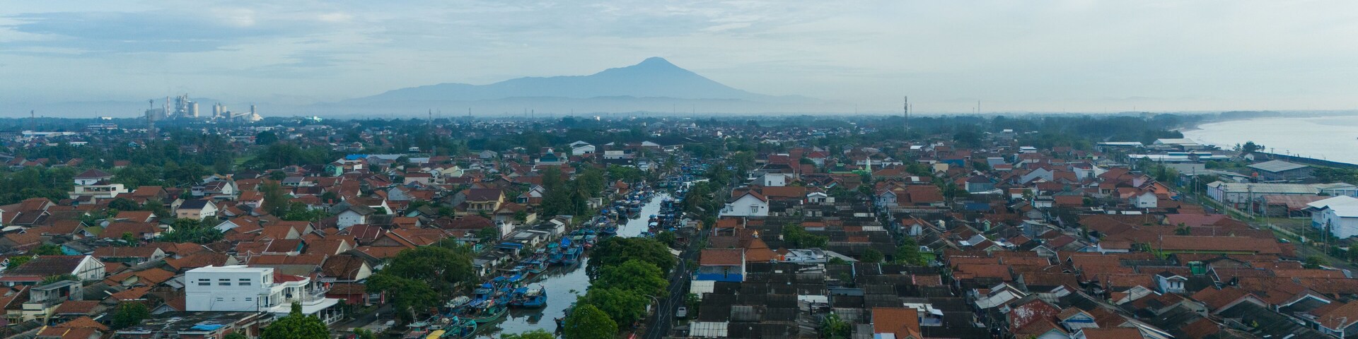 A densely packed urban area with a river running through it, surrounded by residential buildings and a mountain in the background.