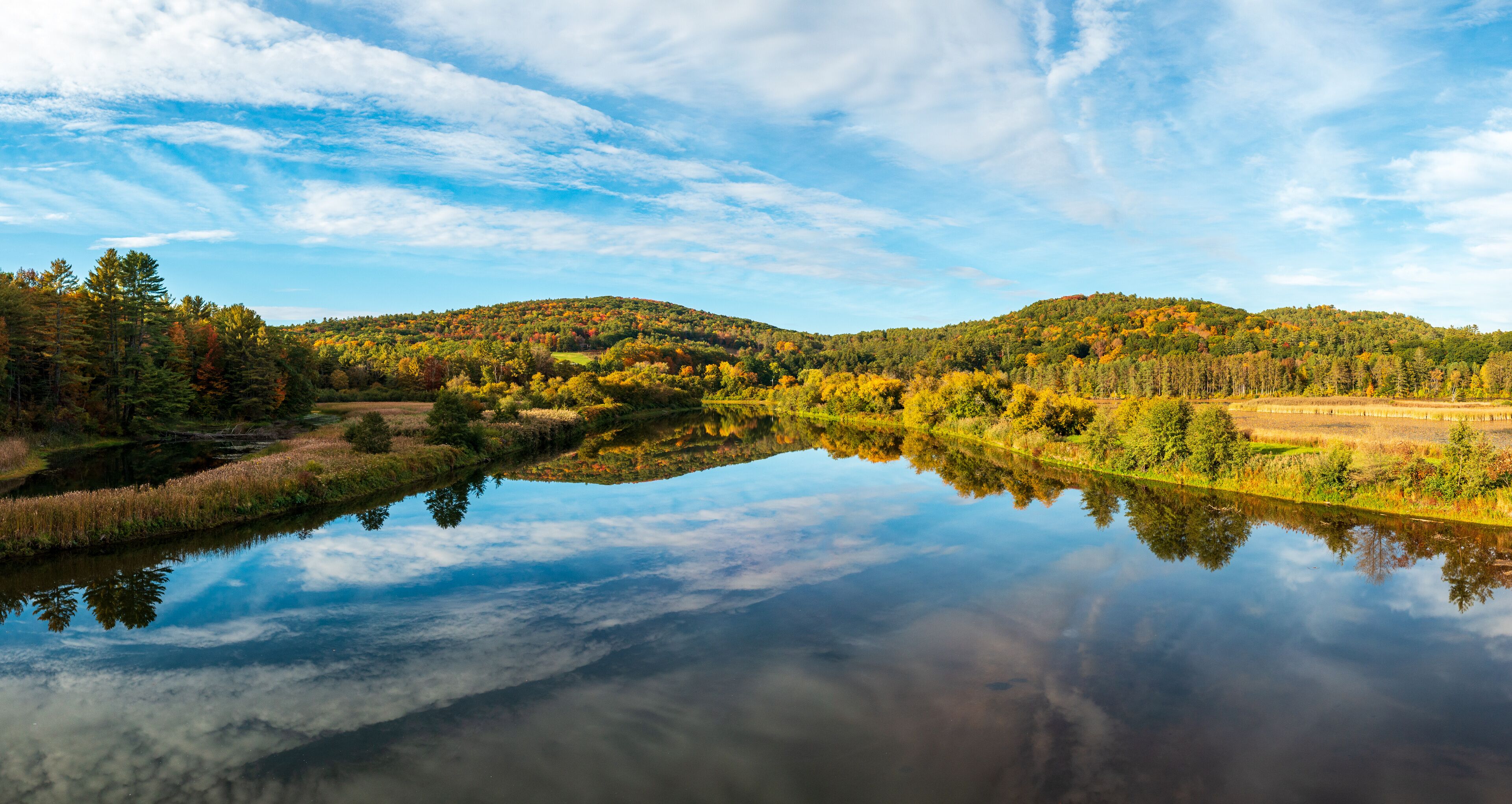 Calm and wide Ottauquechee river flows towards Quechee Gorge in Vermont with fall colors