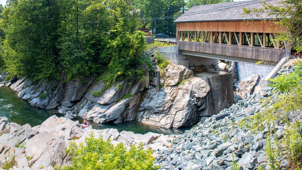 A river with a wooden bridge and a rocky landscape.
