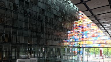 Un edificio moderno con paneles de vidrio reflectante y un vitral de colores.