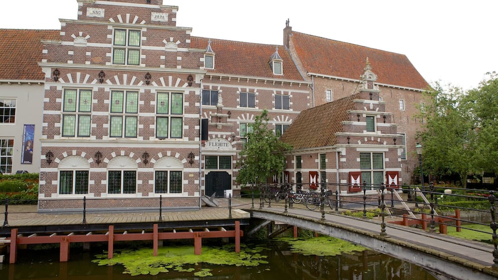 A historic building with a red-tiled roof and a canal in front.