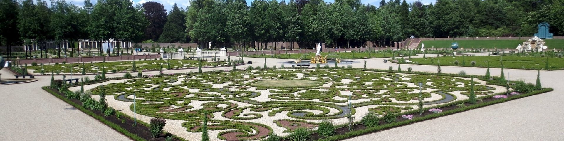 A formal garden with geometric patterns and statues.