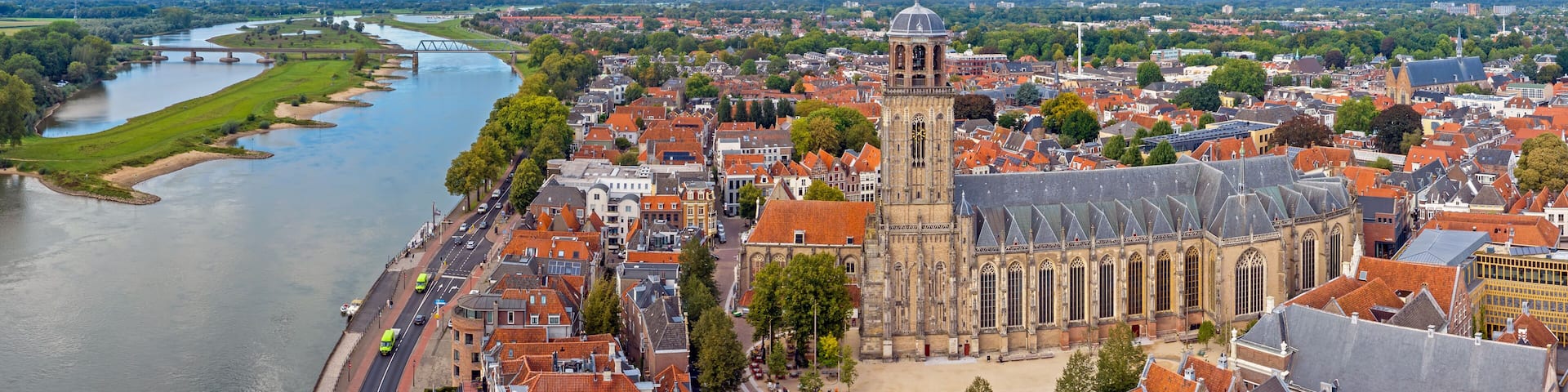 A river flowing through a town with historic buildings and a prominent church with a tall tower.