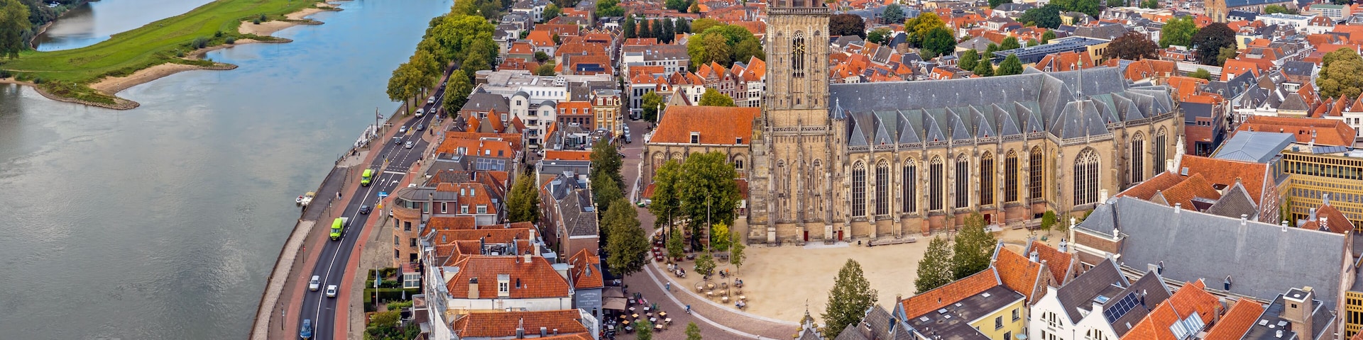 A river flowing through a town with historic buildings and a prominent church with a tall tower.