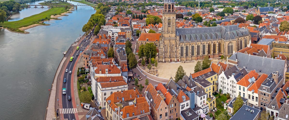 A river flowing through a town with historic buildings and a prominent church with a tall tower.