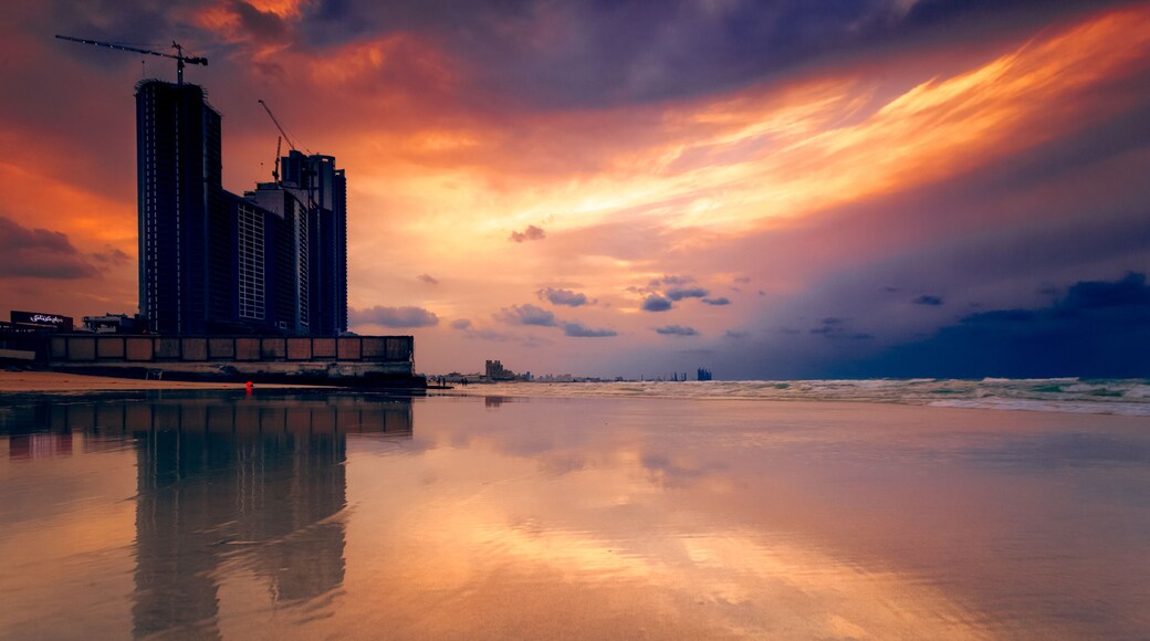 Silhouette of waterfront skyscrapers and cranes at sunset, Ajman, UAE