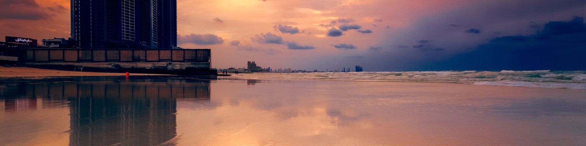 Silhouette of waterfront skyscrapers and cranes at sunset, Ajman, UAE