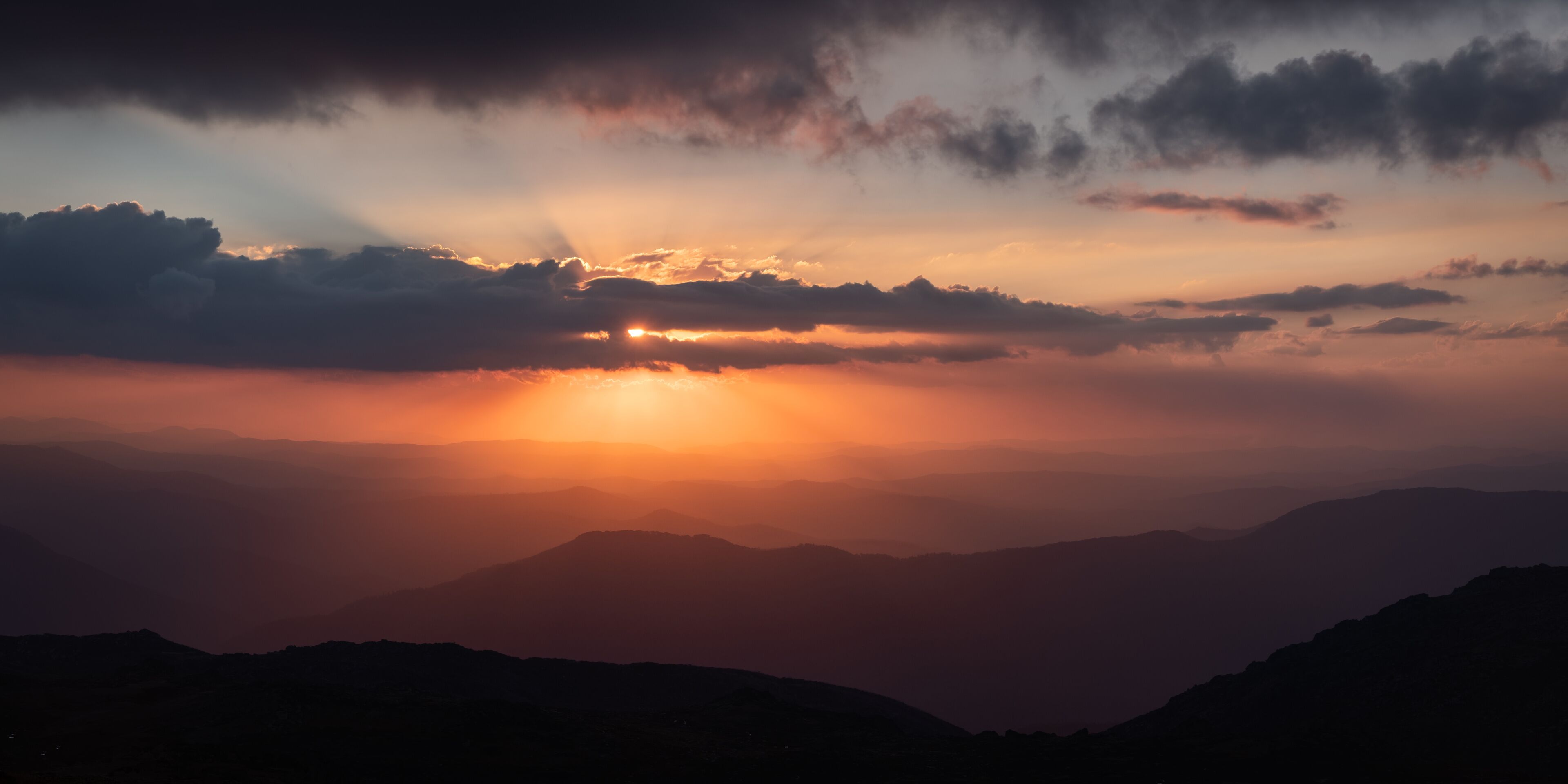 A sunset over a mountain range with clouds.