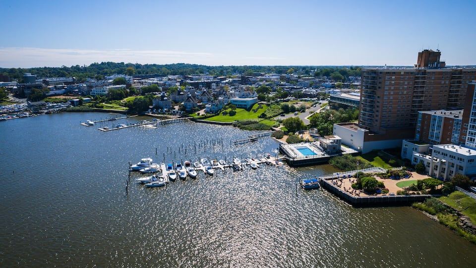 A marina with boats docked, a large building, and a park area.