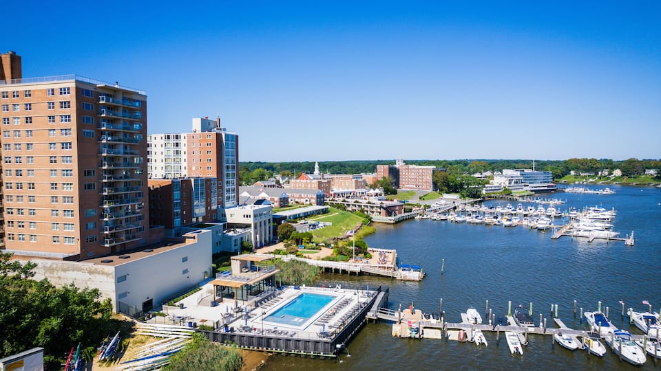 A marina with boats docked, a swimming pool, and surrounding buildings.