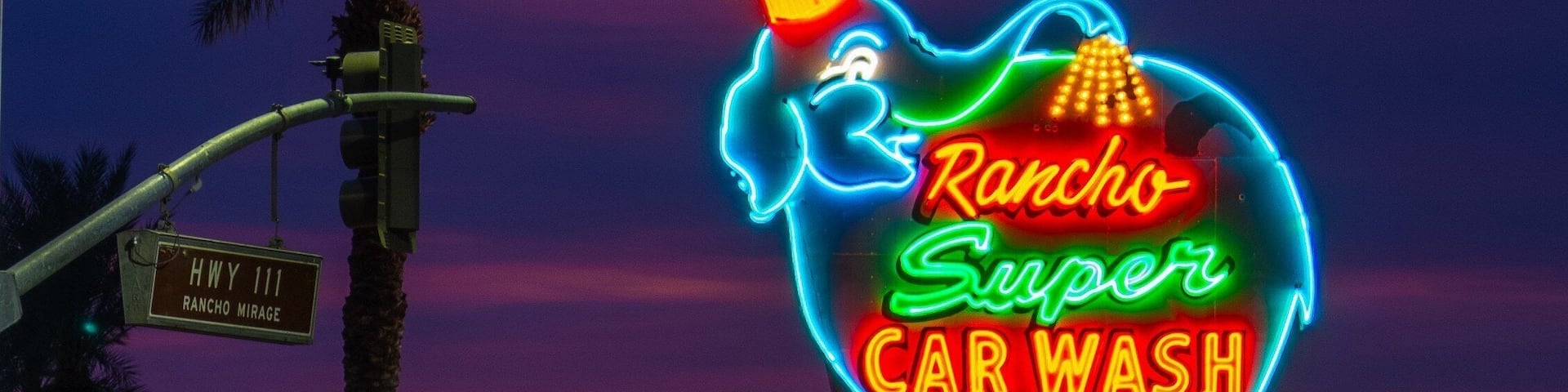 A neon sign for Rancho Super Car Wash against a twilight sky.