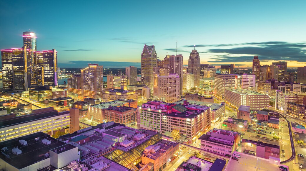 A cityscape at dusk with illuminated buildings and a river in the background.