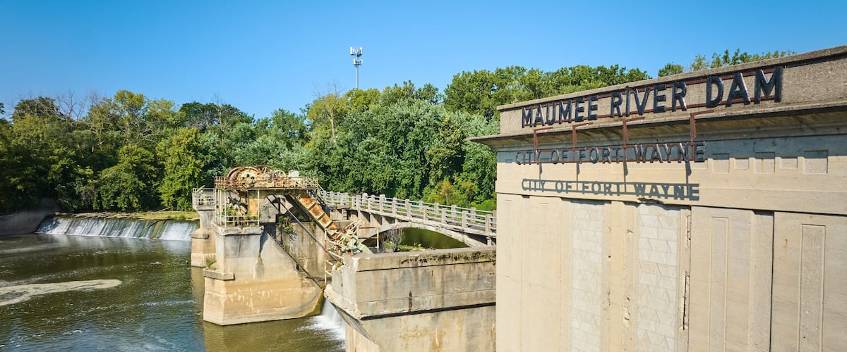 A dam with a bridge, labeled "Maumee River Dam," and a sign for the "City of Fort Wayne."
