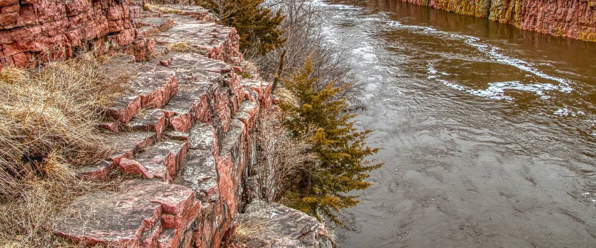A river flowing through a canyon with red rock formations on both sides.