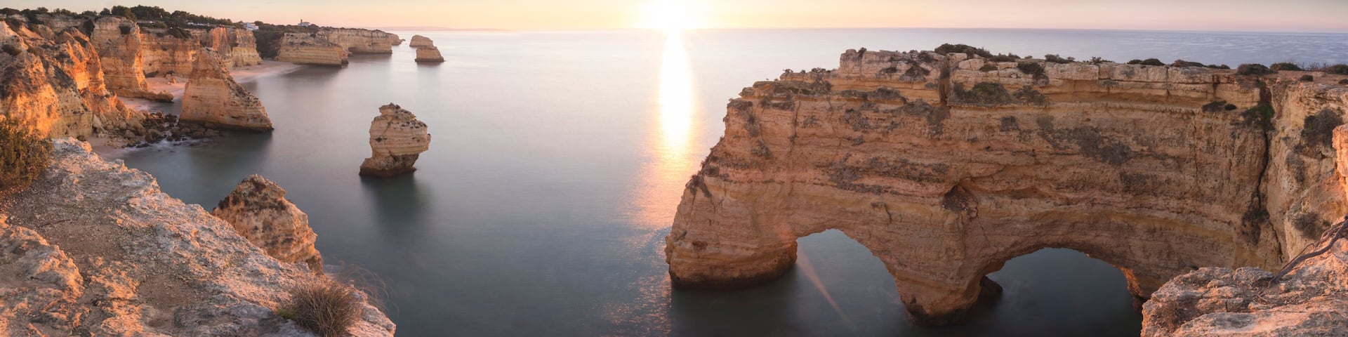 A coastal landscape with rock formations and a clear sky.
