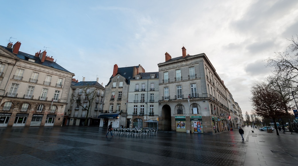 Una plaça europea històrica amb arquitectura clàssica, incloent un edifici destacat amb un gran arc i estructures adjacents més petites.