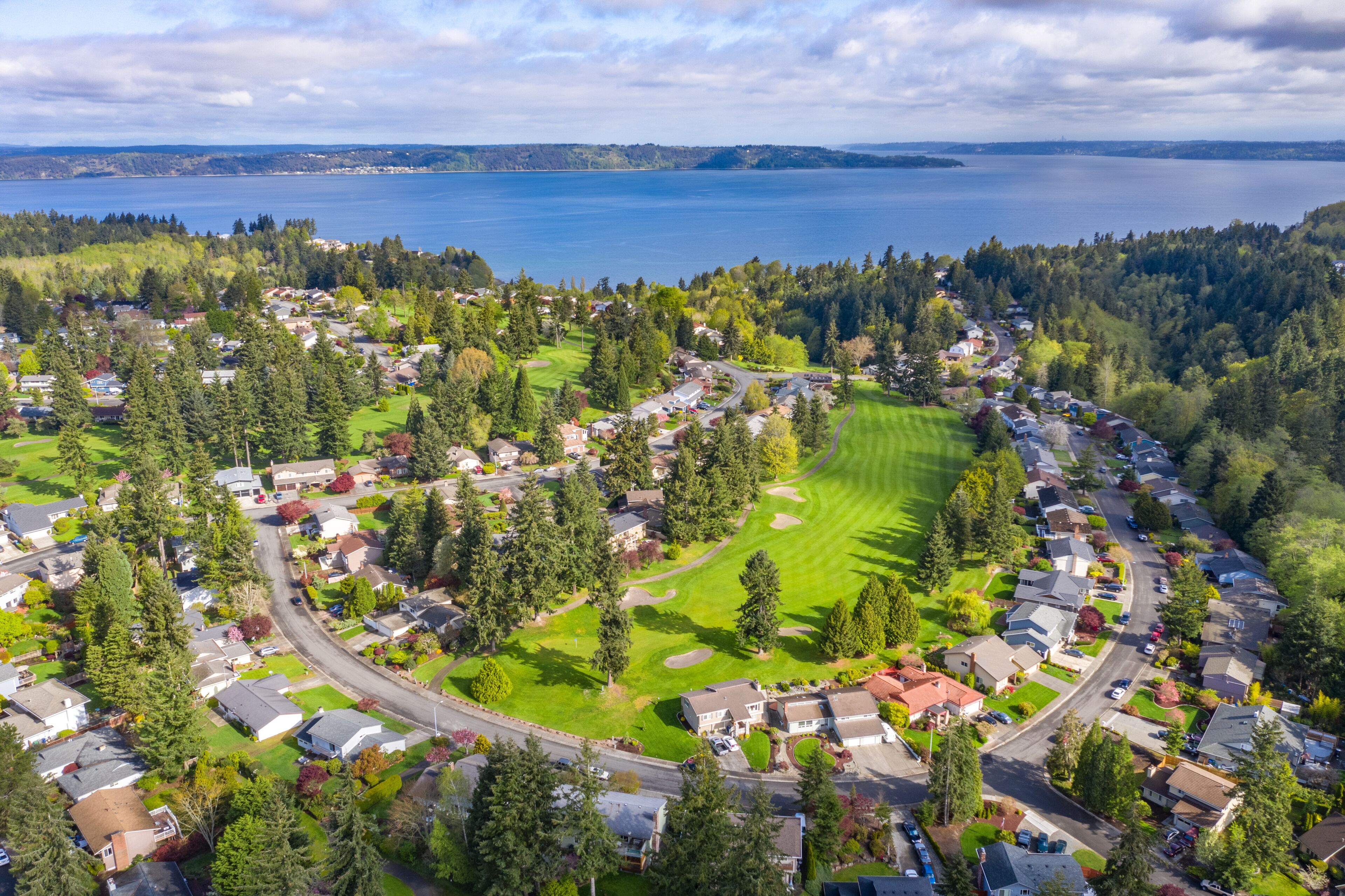 Una zona residencial con casas, un campo de golf y un lago.