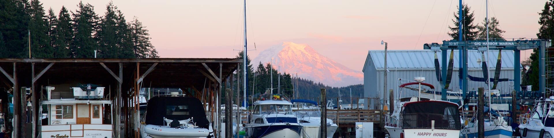A marina with boats docked, a mountain in the background, and a building labeled 'GIG HARBOR MARINA'.