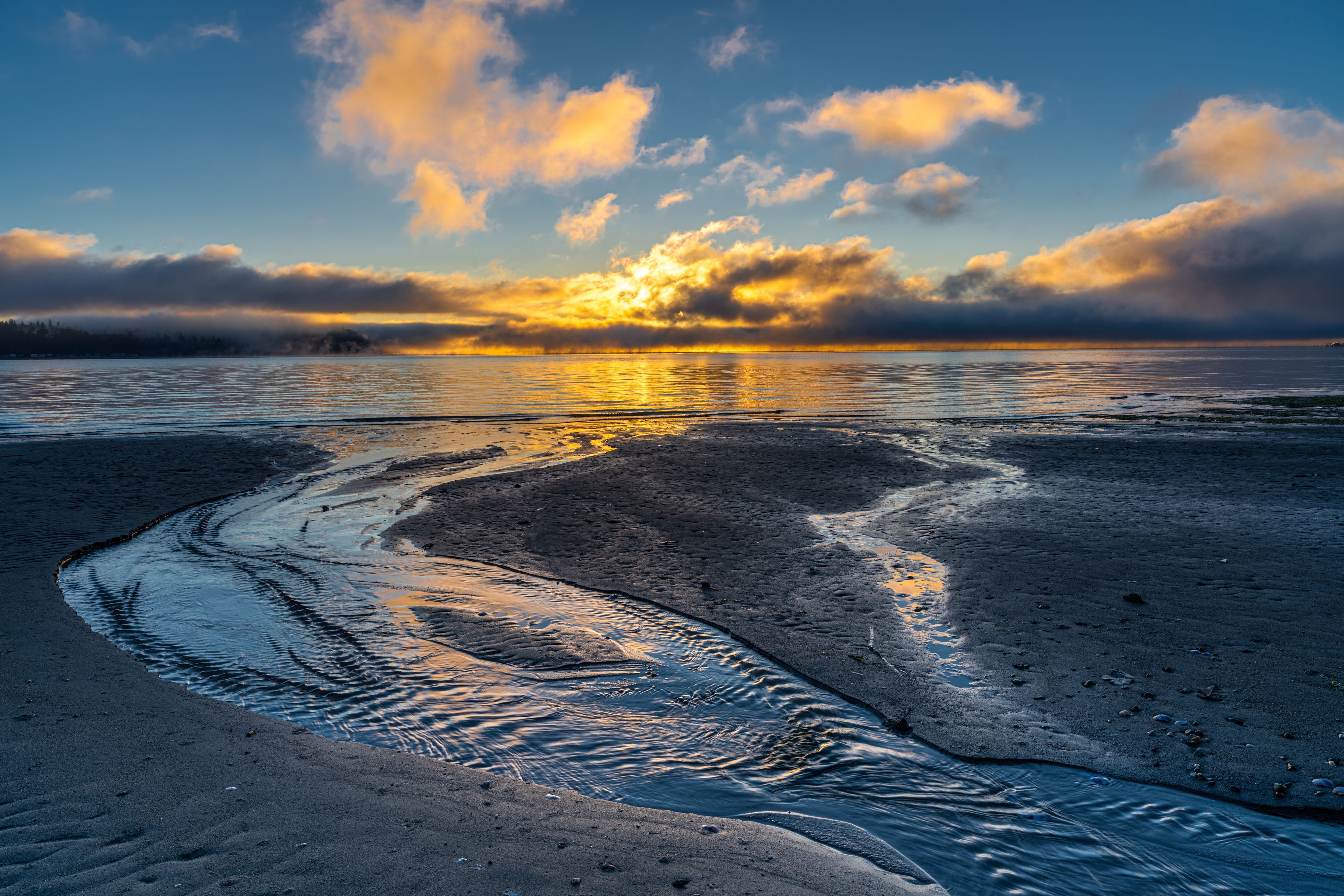 A sunset over a beach with waves lapping onto the shore.