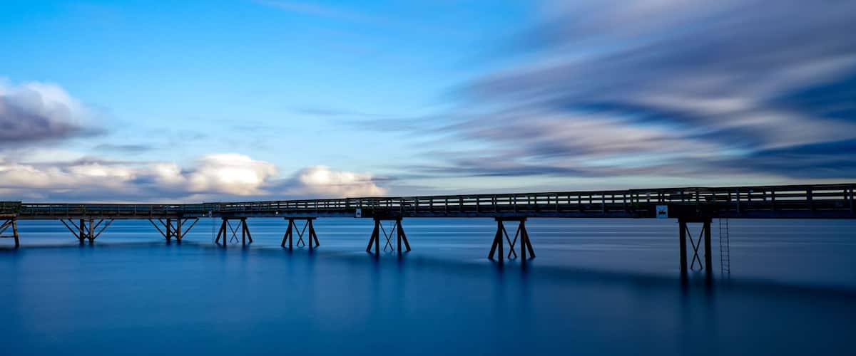 A long pier extending into calm waters under a twilight sky.