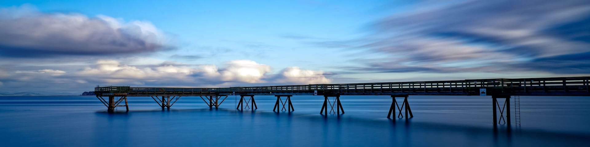 A long pier extending into calm waters under a twilight sky.