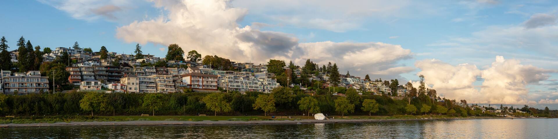 White Rock, British Columbia, Canada. Beautiful Panoramic View of Residential Homes on the Ocean Shore during a sunny and cloudy summer sunset.