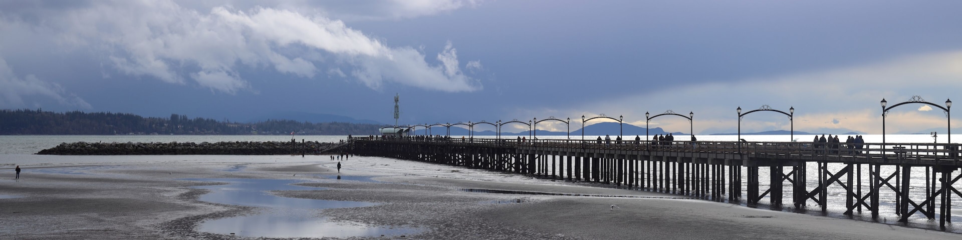 Un muelle se adentra en un mar tranquilo bajo un cielo nublado.