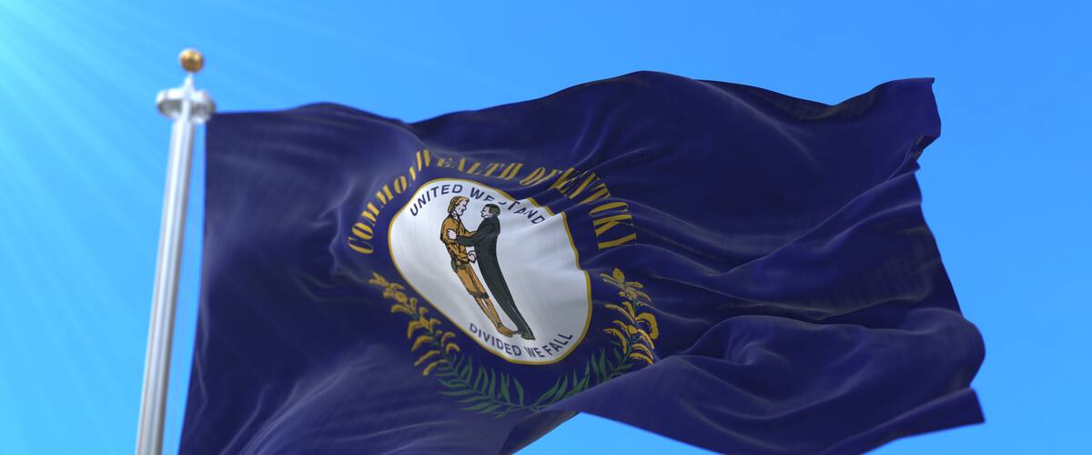 A flag with a white emblem featuring a woman and a man, surrounded by text and a laurel wreath.