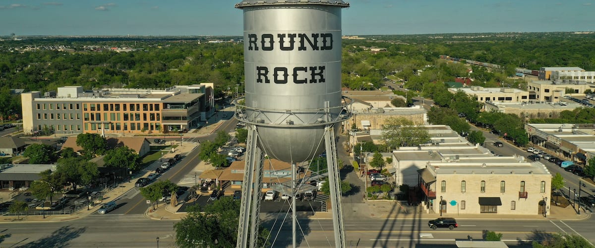 Vesitorni, jossa lukee suurilla kirjaimilla ”ROUND ROCK”, taustalla kirkkaan sininen taivas ja kaupunkimaisema.