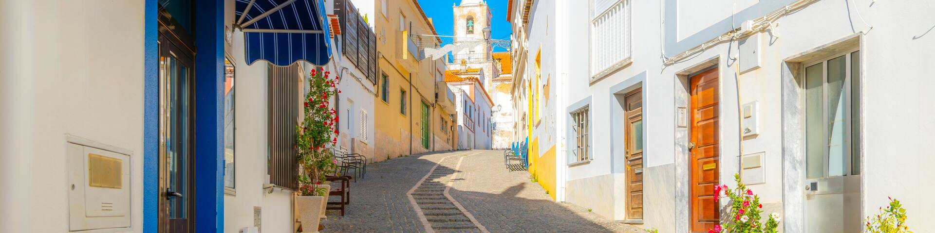 The bell tower of the Church of San Sebastian seen from the Rua dos Ferreiros, a cobblestone hillside street in the historic old town of Lagos, on the Algarve coast of Portugal.