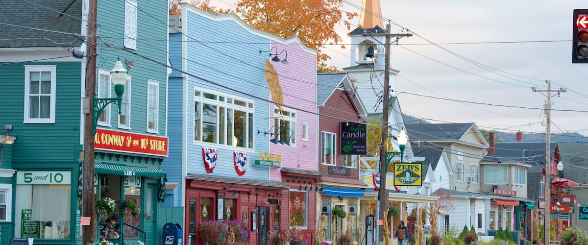 Una calle colorida con diversas tiendas, incluyendo una tienda de todo, una tienda de velas y una tienda de ultramarinos.