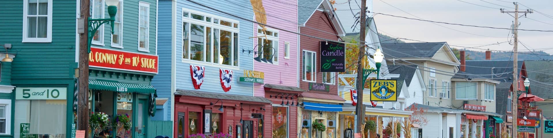 A colorful street with various shops, including a 5 and 10 store, a candle shop, and a general store.