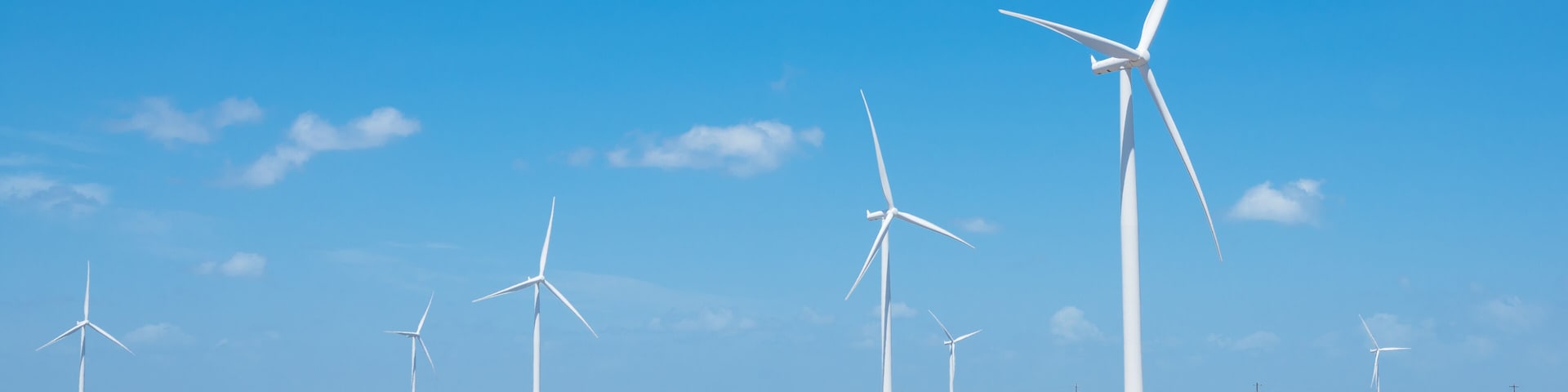 A wind farm with multiple wind turbines in a field under a clear blue sky.