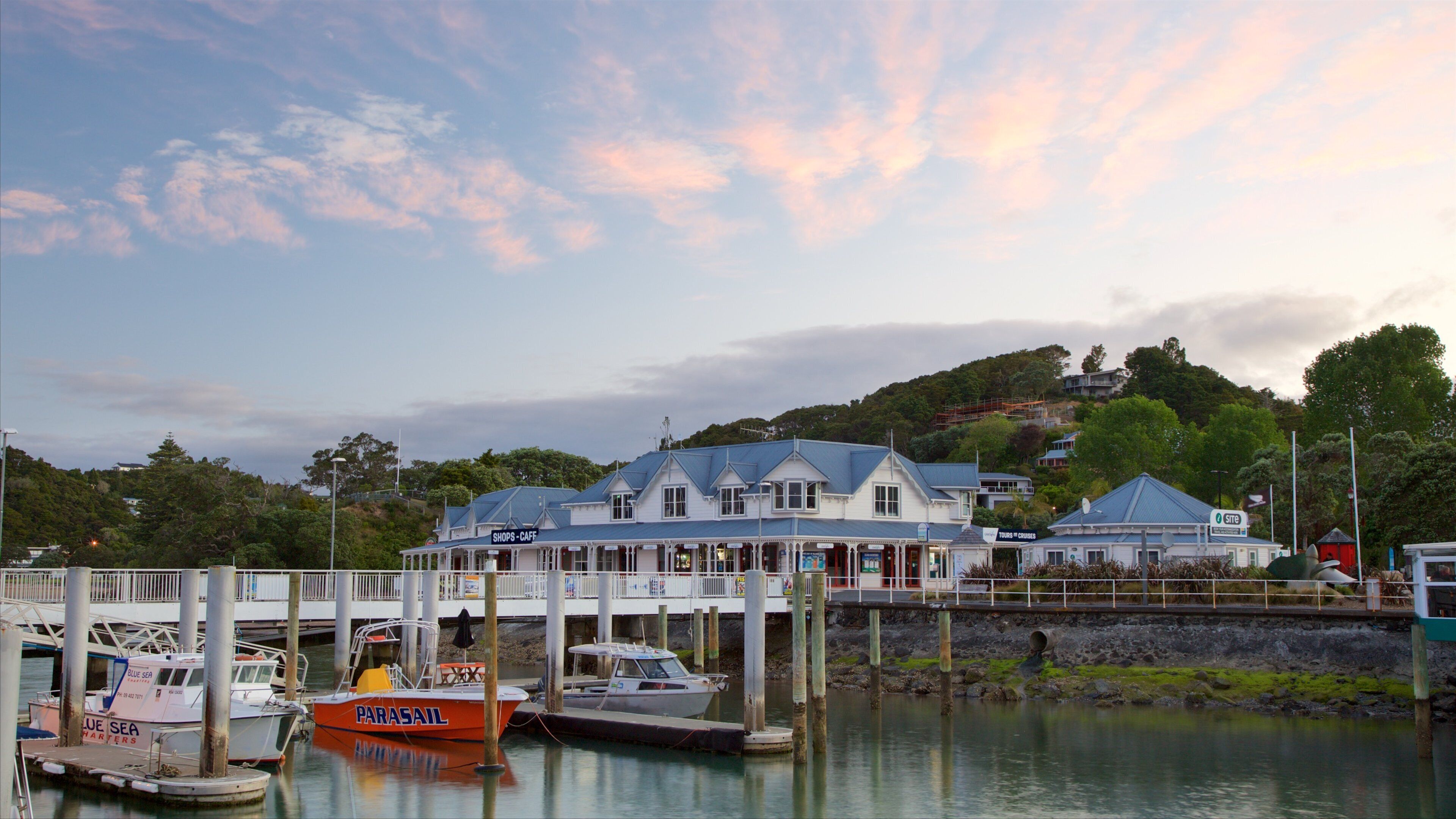 A waterfront with a white building labeled 'Shops-Cafe' and a boat named 'Parasil'.
