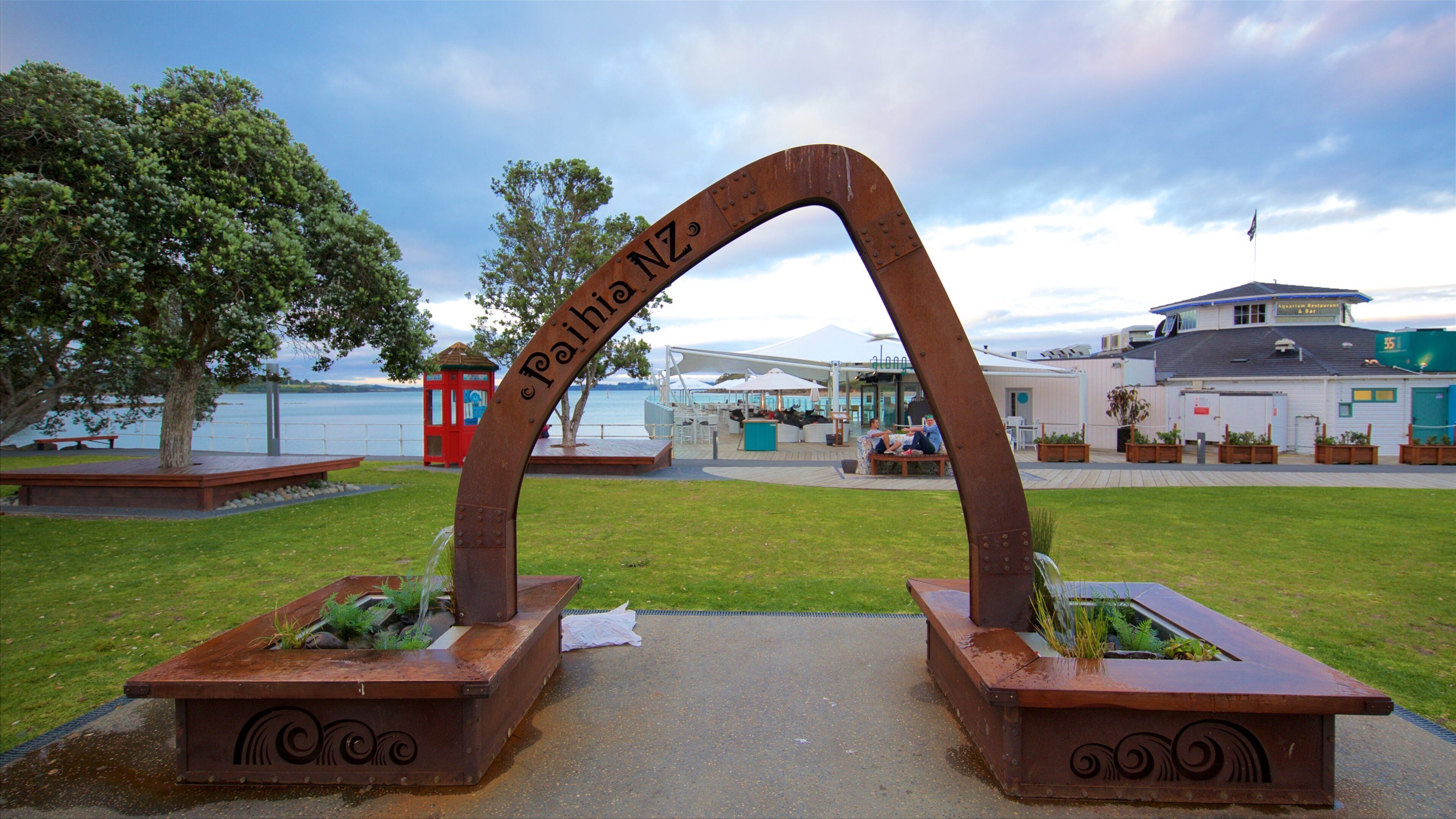 A metal archway with the inscription "Pailah NZ" and a red telephone booth in the background.