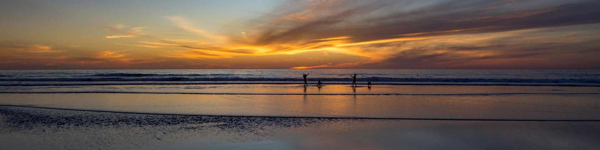 Una playa al atardecer con olas y cielo despejado.