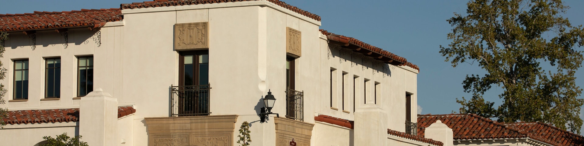 Un edificio histórico con fachada blanca, tejado de tejas rojas y detalles arquitectónicos ornamentales.