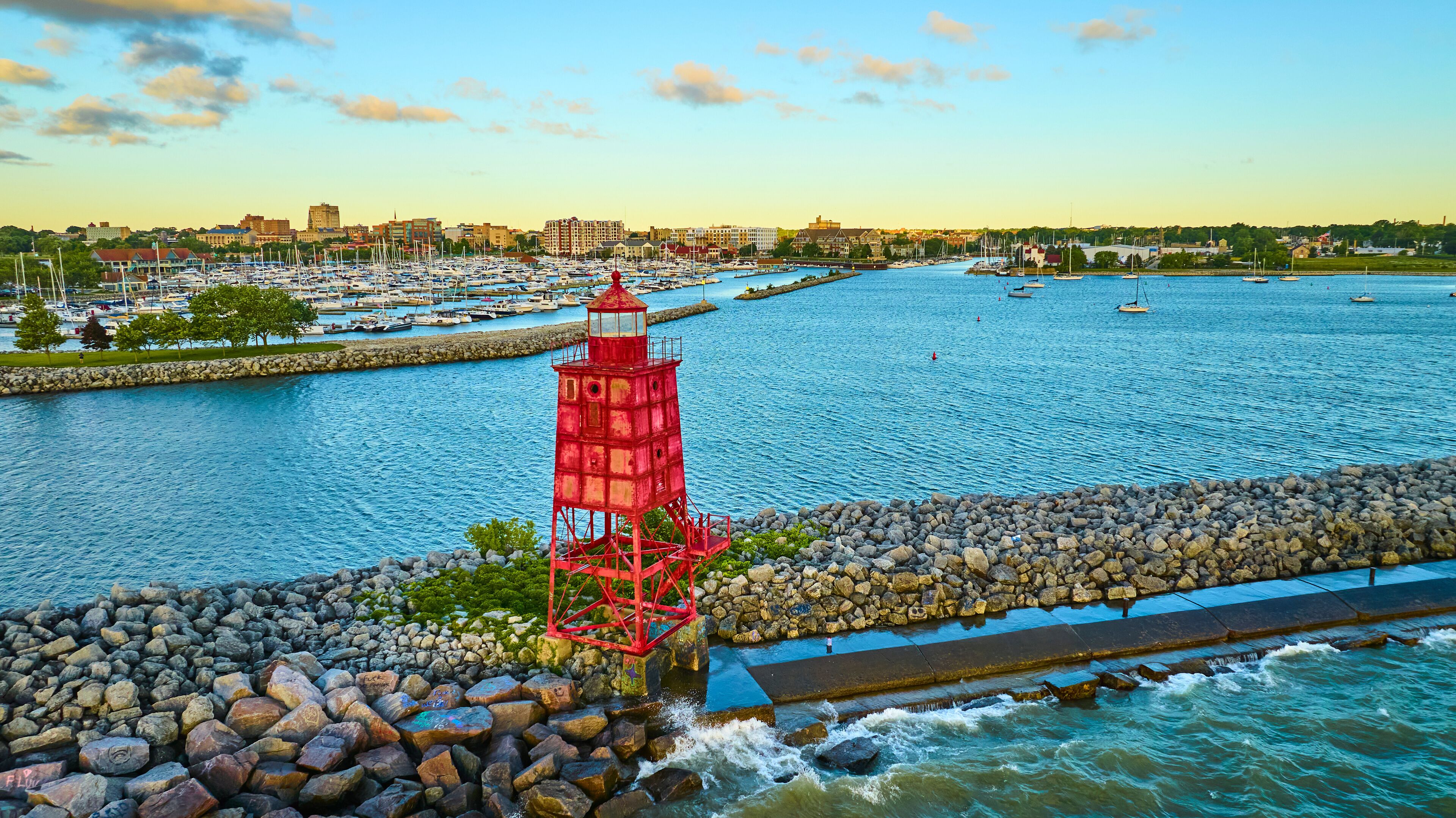 Aerial View of Vibrant Red Lighthouse at Sunset Over Calm Marina