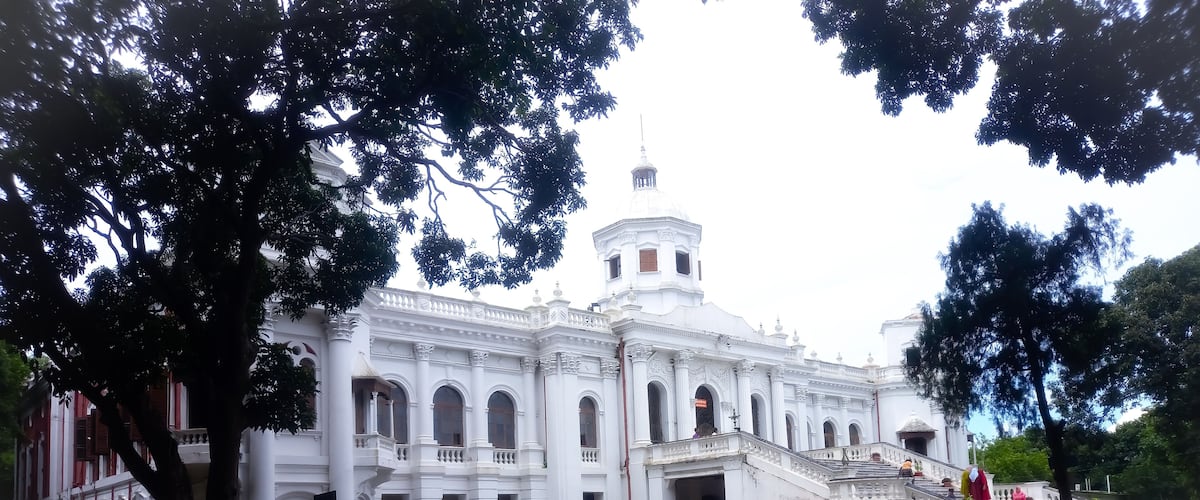 A large white building with a dome and a staircase leading to the entrance.